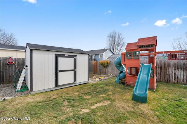 view of playground with a storage shed, a fenced backyard, a lawn, and an outbuilding