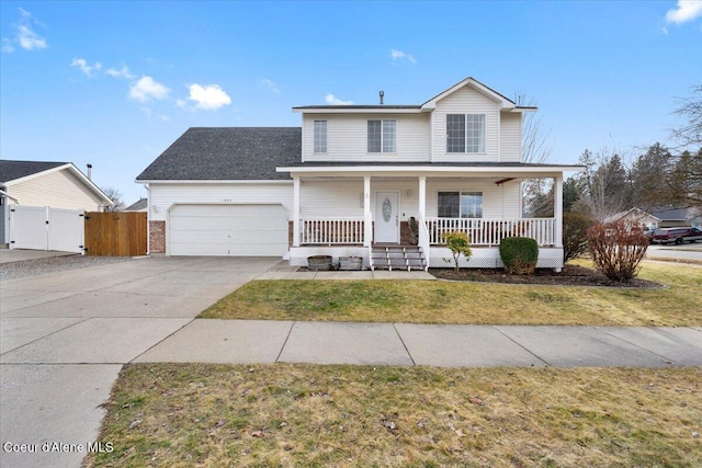 traditional-style home featuring an attached garage, covered porch, concrete driveway, a gate, and a front yard