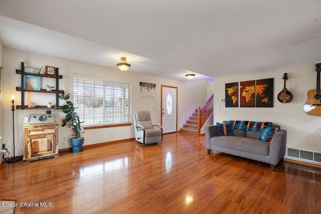 living area with stairs, wood finished floors, visible vents, and baseboards