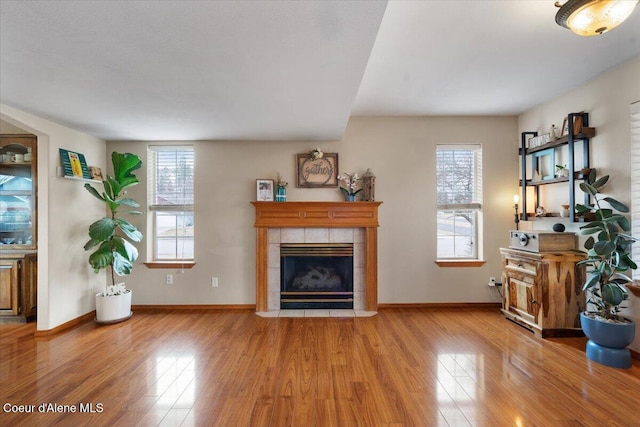 living room with a wealth of natural light, a tile fireplace, and wood finished floors