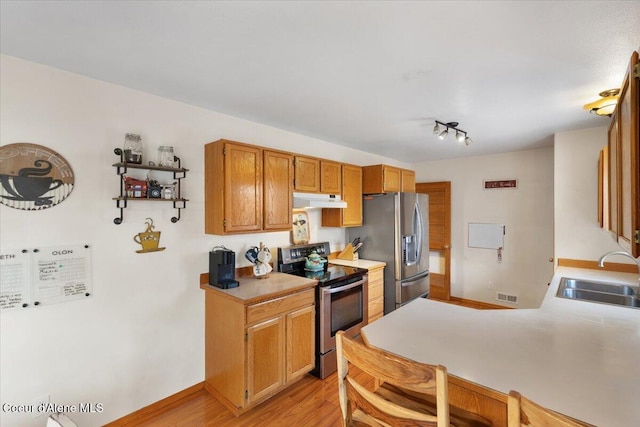 kitchen with under cabinet range hood, stainless steel appliances, a sink, visible vents, and light countertops