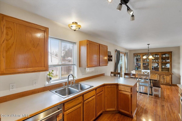 kitchen featuring light wood-style floors, light countertops, a sink, and a peninsula