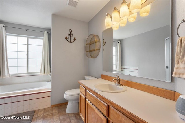 bathroom with toilet, tiled tub, visible vents, and vanity