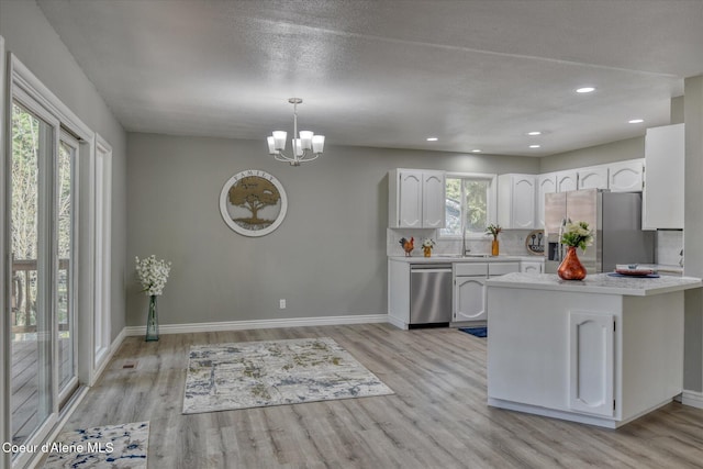 kitchen featuring light wood-type flooring, a sink, white cabinetry, stainless steel appliances, and light countertops