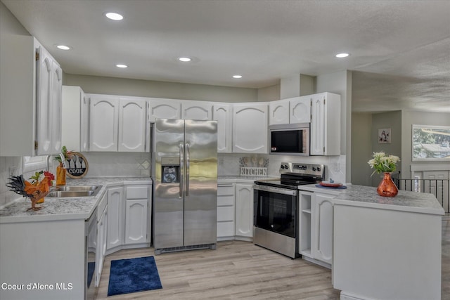 kitchen featuring light wood finished floors, appliances with stainless steel finishes, white cabinetry, and light countertops