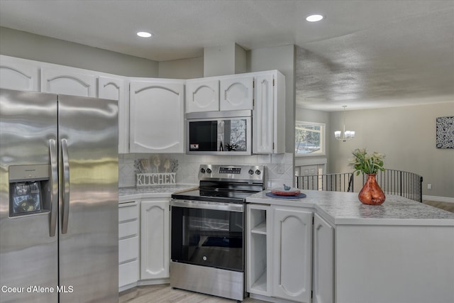 kitchen with backsplash, appliances with stainless steel finishes, white cabinetry, and a peninsula