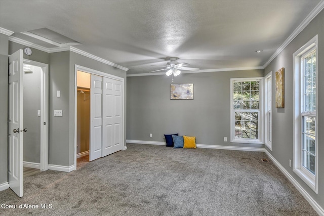 unfurnished bedroom with a ceiling fan, a closet, carpet floors, crown molding, and baseboards