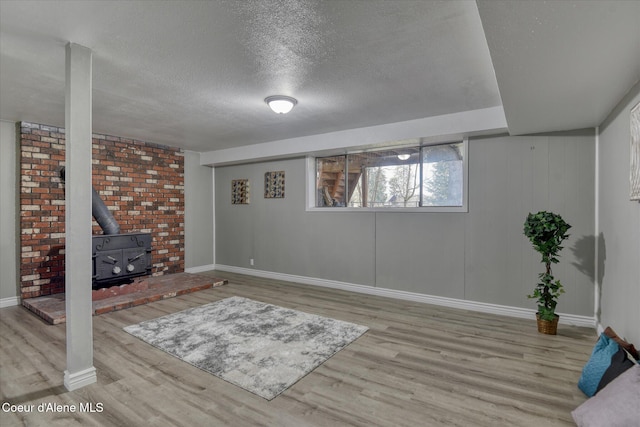 below grade area with baseboards, a textured ceiling, wood finished floors, and a wood stove