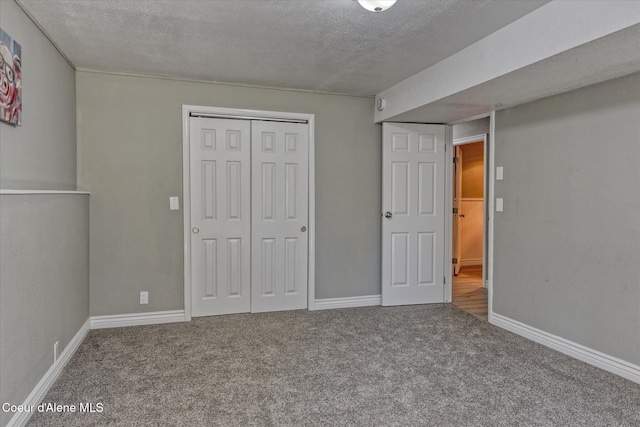 unfurnished bedroom featuring a closet, carpet floors, a textured ceiling, and baseboards