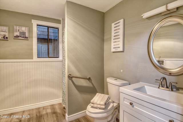 bathroom with wainscoting, toilet, vanity, and wood finished floors