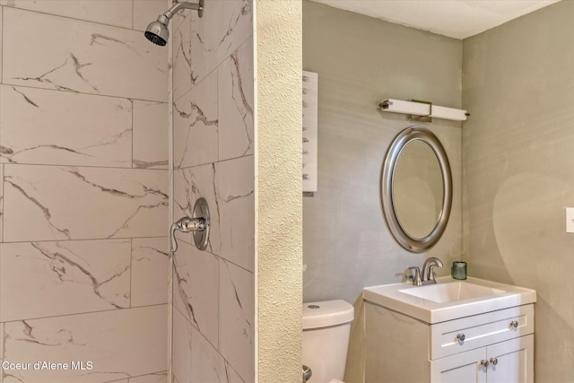 full bathroom featuring toilet, tiled shower, and vanity