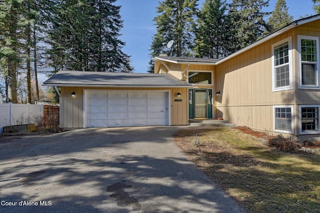 view of front facade featuring driveway, a garage, and fence