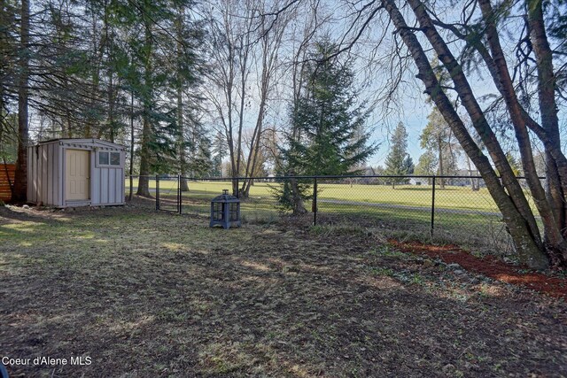 view of yard featuring a storage unit, an outdoor structure, and fence