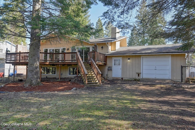 back of property with stairway, a wooden deck, a lawn, a chimney, and a garage