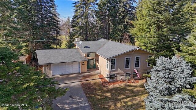 view of front of home with a chimney, driveway, an attached garage, and roof with shingles