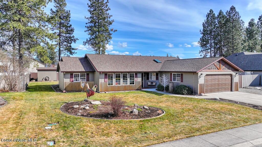 ranch-style home featuring driveway, fence, roof with shingles, a front yard, and a garage