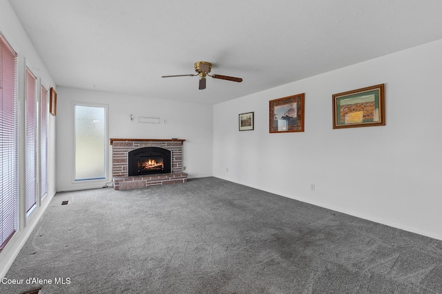 unfurnished living room featuring carpet, ceiling fan, and a brick fireplace