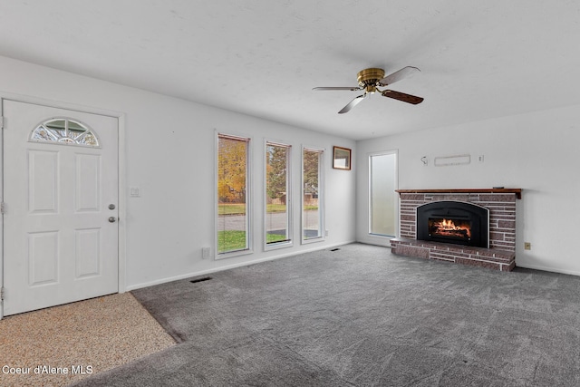 unfurnished living room featuring visible vents, baseboards, a ceiling fan, carpet, and a brick fireplace