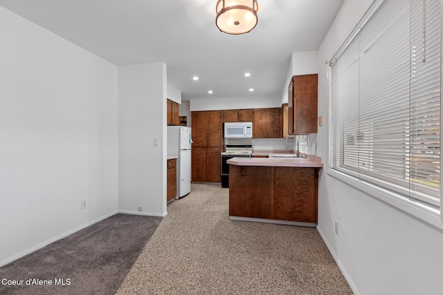 kitchen with recessed lighting, light countertops, white appliances, a peninsula, and baseboards