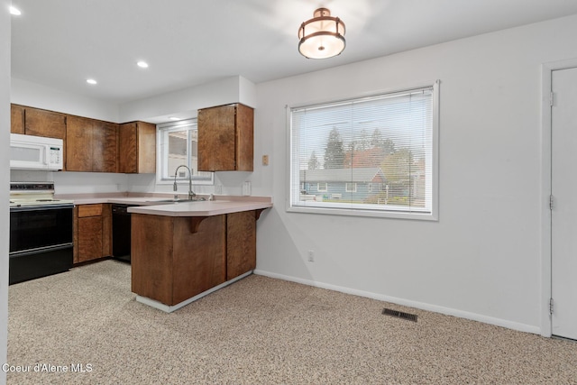 kitchen with white appliances, baseboards, a peninsula, light countertops, and a sink