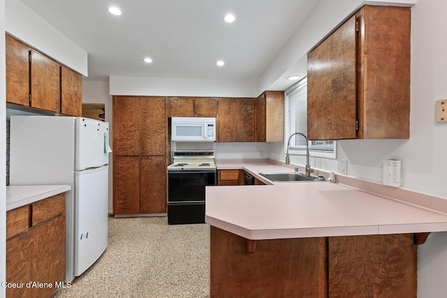 kitchen featuring recessed lighting, a peninsula, white appliances, a sink, and light countertops