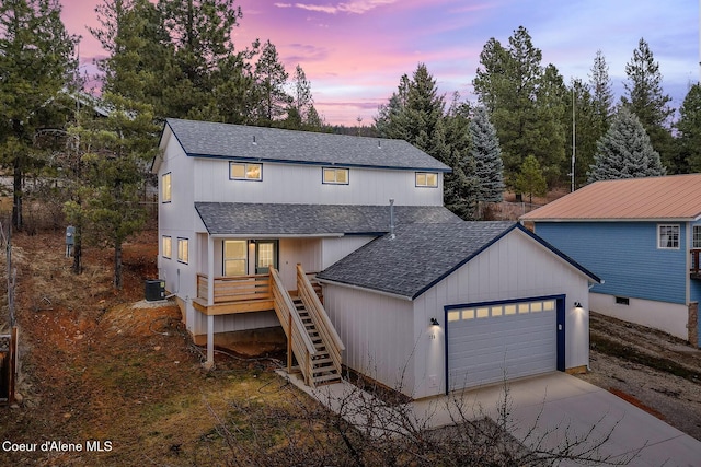 modern farmhouse with driveway, roof with shingles, an attached garage, stairs, and central air condition unit