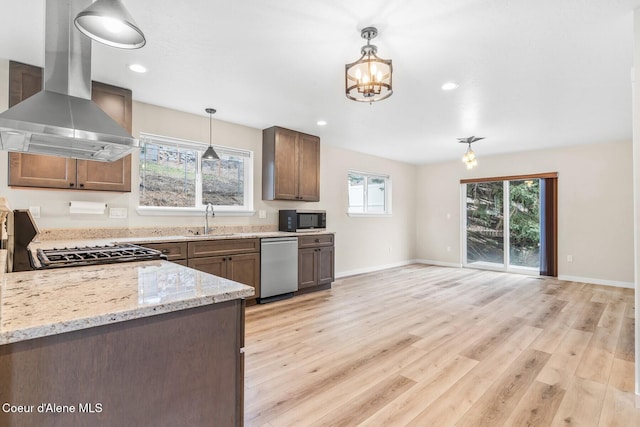 kitchen featuring wall chimney exhaust hood, appliances with stainless steel finishes, a sink, and light wood-style floors