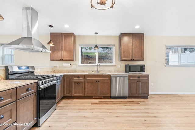 kitchen featuring appliances with stainless steel finishes, light wood-style floors, island exhaust hood, and a sink