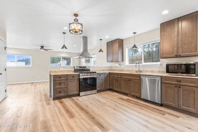 kitchen with stainless steel appliances, a peninsula, a sink, light wood-type flooring, and island exhaust hood