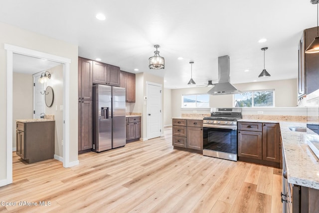 kitchen featuring light stone counters, decorative light fixtures, extractor fan, stainless steel appliances, and light wood-type flooring