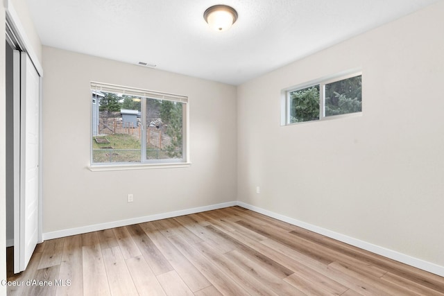 unfurnished bedroom with a closet, visible vents, baseboards, and wood finished floors