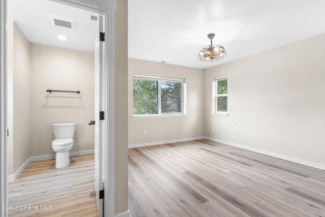 bathroom with toilet, visible vents, baseboards, and wood finished floors