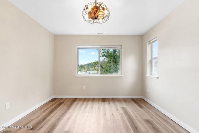 unfurnished room featuring light wood finished floors, visible vents, and baseboards