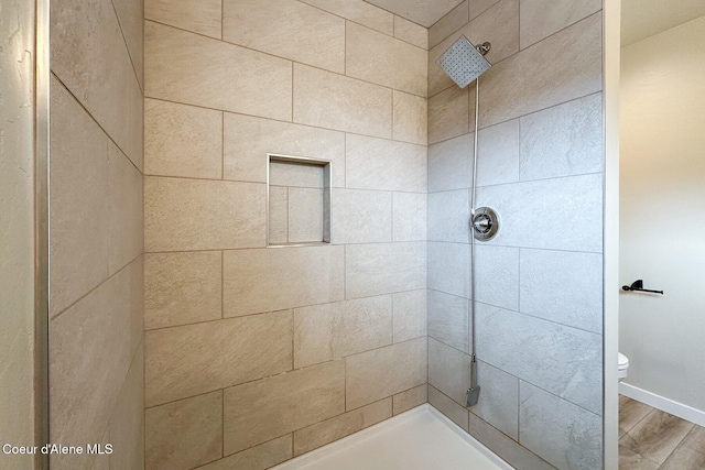 bathroom featuring tiled shower, wood finished floors, and toilet