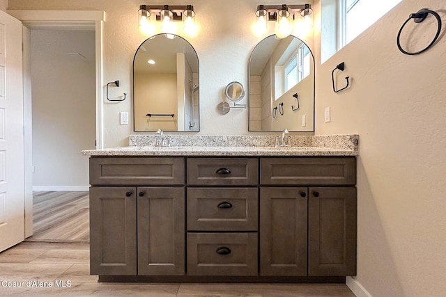 bathroom featuring double vanity, a sink, baseboards, and wood finished floors