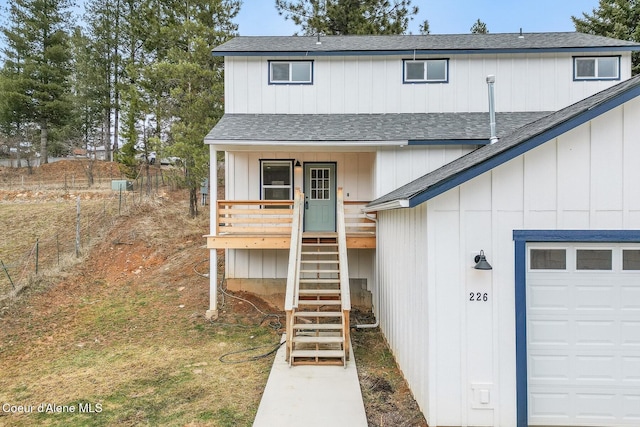 view of front of home with a garage, a shingled roof, covered porch, stairs, and fence