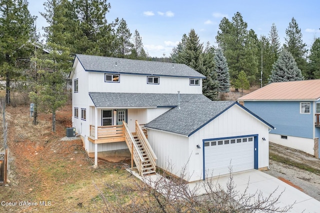 view of front of property with a garage, a shingled roof, concrete driveway, stairs, and central air condition unit