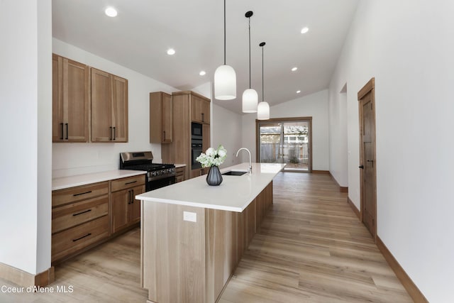 kitchen featuring a kitchen island with sink, a sink, light countertops, light wood-type flooring, and black appliances