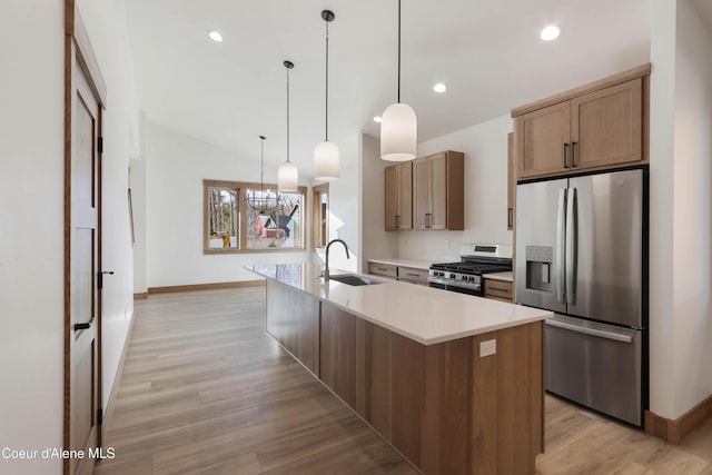 kitchen featuring stainless steel appliances, recessed lighting, light countertops, a sink, and light wood-type flooring