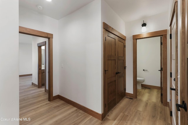 hall featuring light wood-style flooring and baseboards