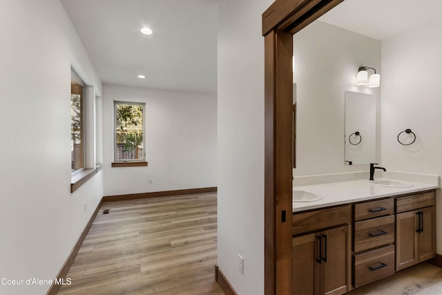 bathroom featuring double vanity, recessed lighting, a sink, wood finished floors, and baseboards