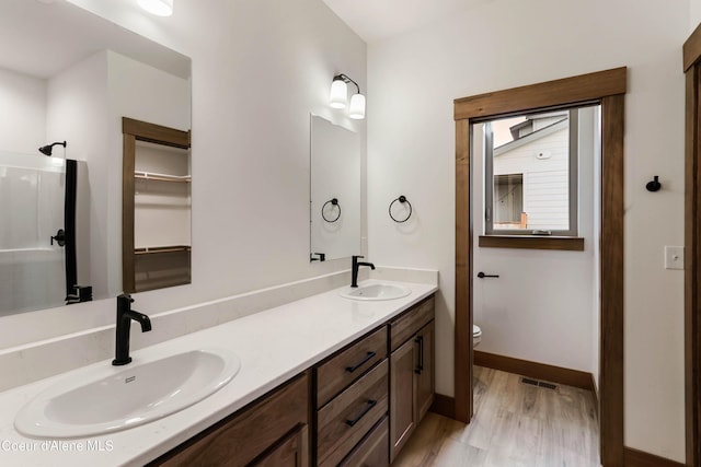 bathroom with baseboards, a sink, toilet, and double vanity