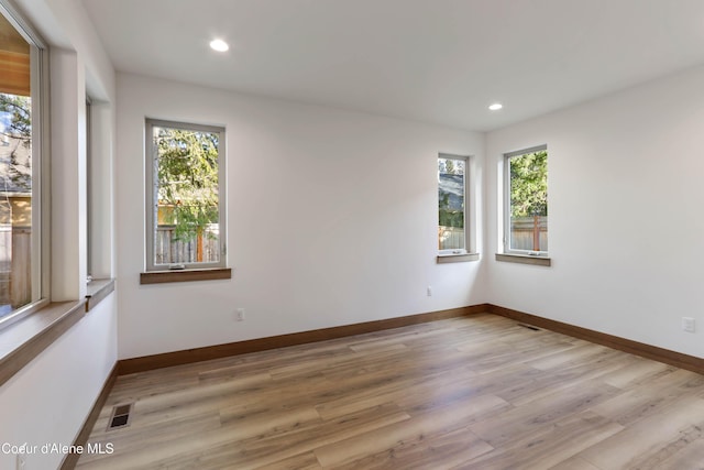 unfurnished room with baseboards, plenty of natural light, visible vents, and wood finished floors