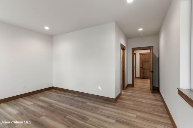 empty room with light wood-style floors, recessed lighting, and baseboards