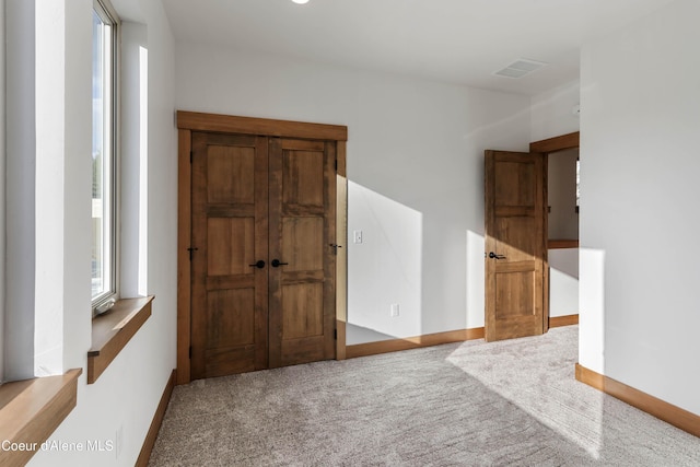 unfurnished room featuring carpet flooring, visible vents, and baseboards