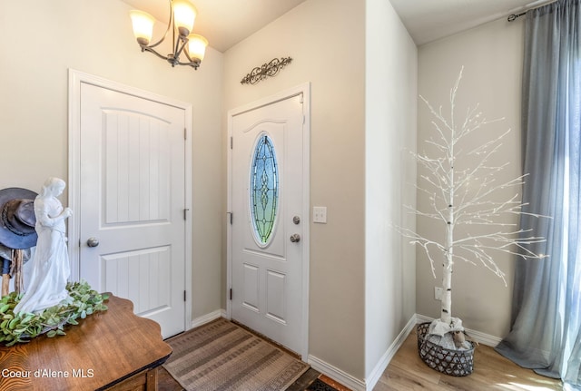 foyer entrance featuring baseboards, wood finished floors, and an inviting chandelier