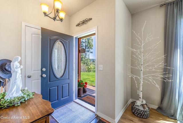 entryway featuring a chandelier, wood finished floors, and baseboards