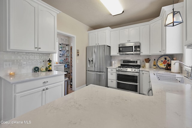 kitchen featuring appliances with stainless steel finishes, a sink, white cabinets, and light stone countertops