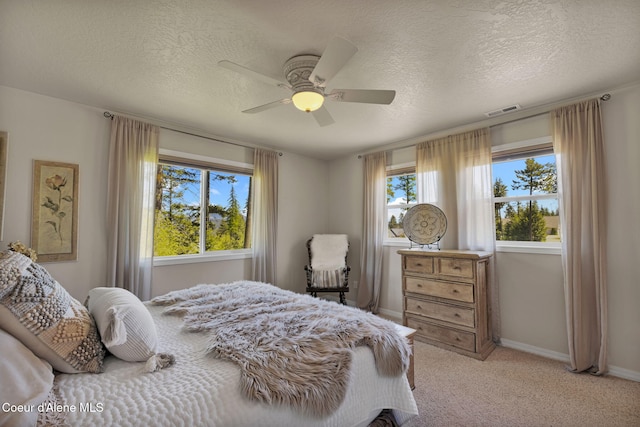 bedroom featuring baseboards, visible vents, a textured ceiling, and light colored carpet