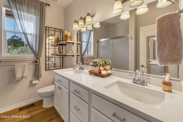 full bathroom with wood finished floors, a sink, visible vents, and a shower stall